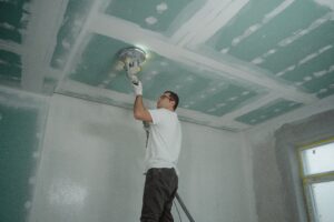 A skilled worker sanding the ceiling for a home remodeling